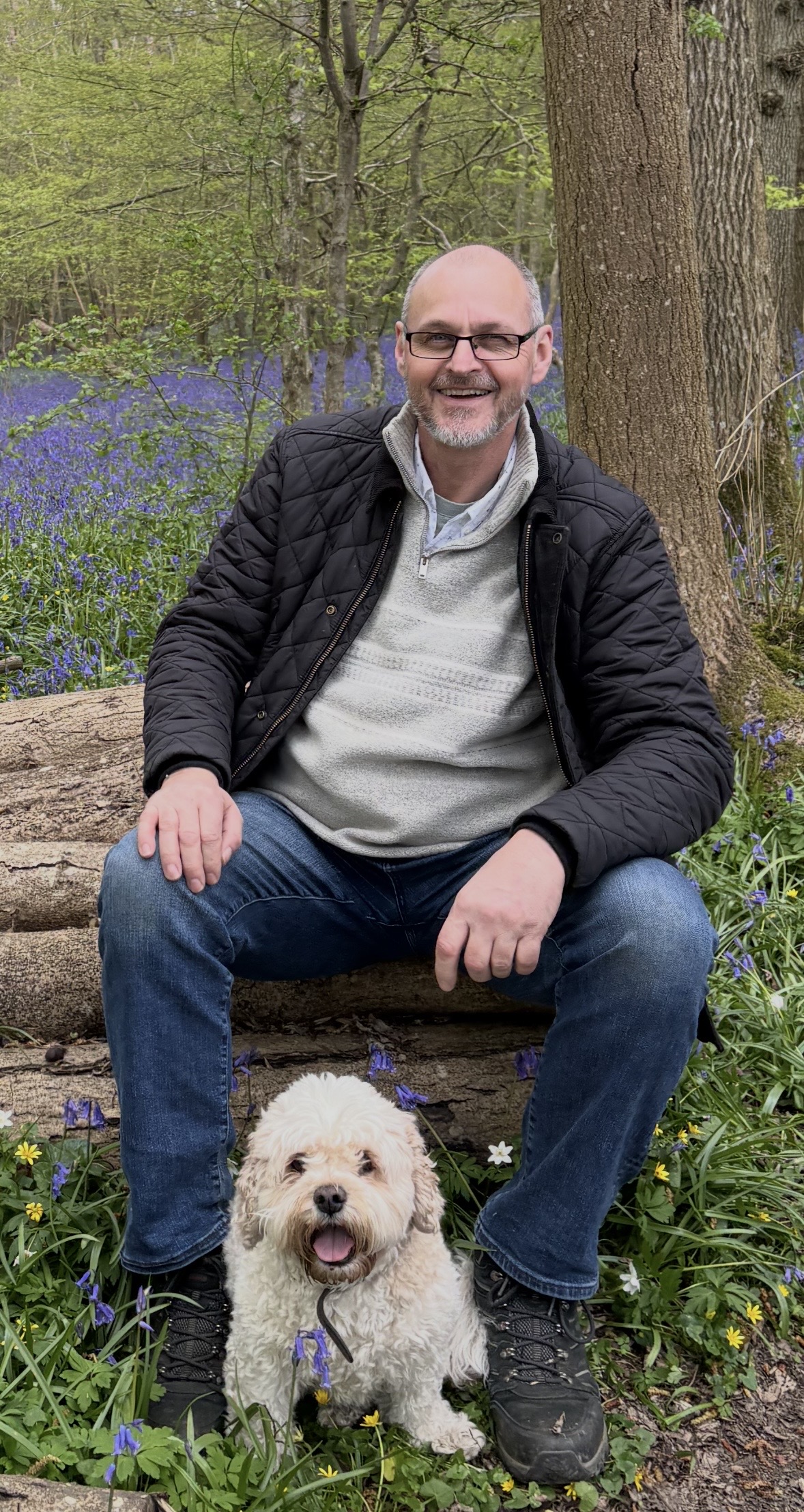 Tim Riley, ADHD Coach, sitting in a bluebell wood with his dog